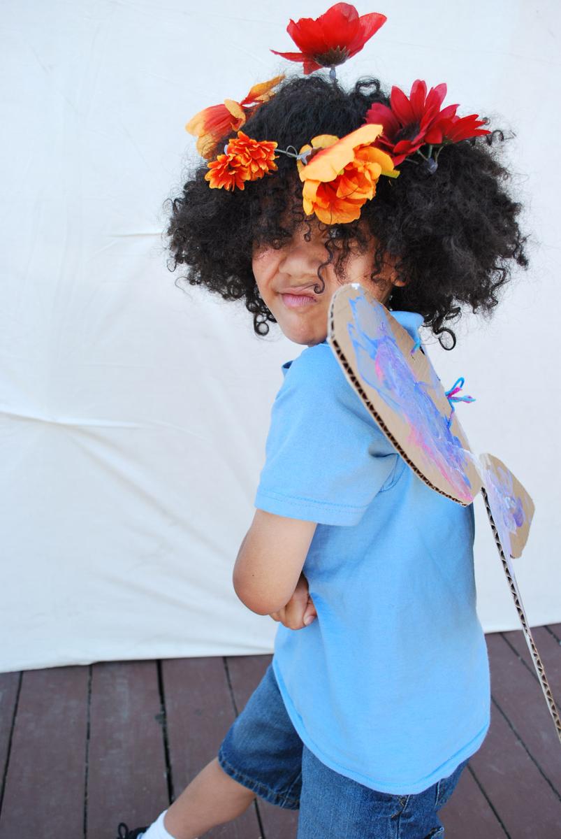 一个穿着戏服，头戴纸板翅膀，头戴鲜花的孩子.